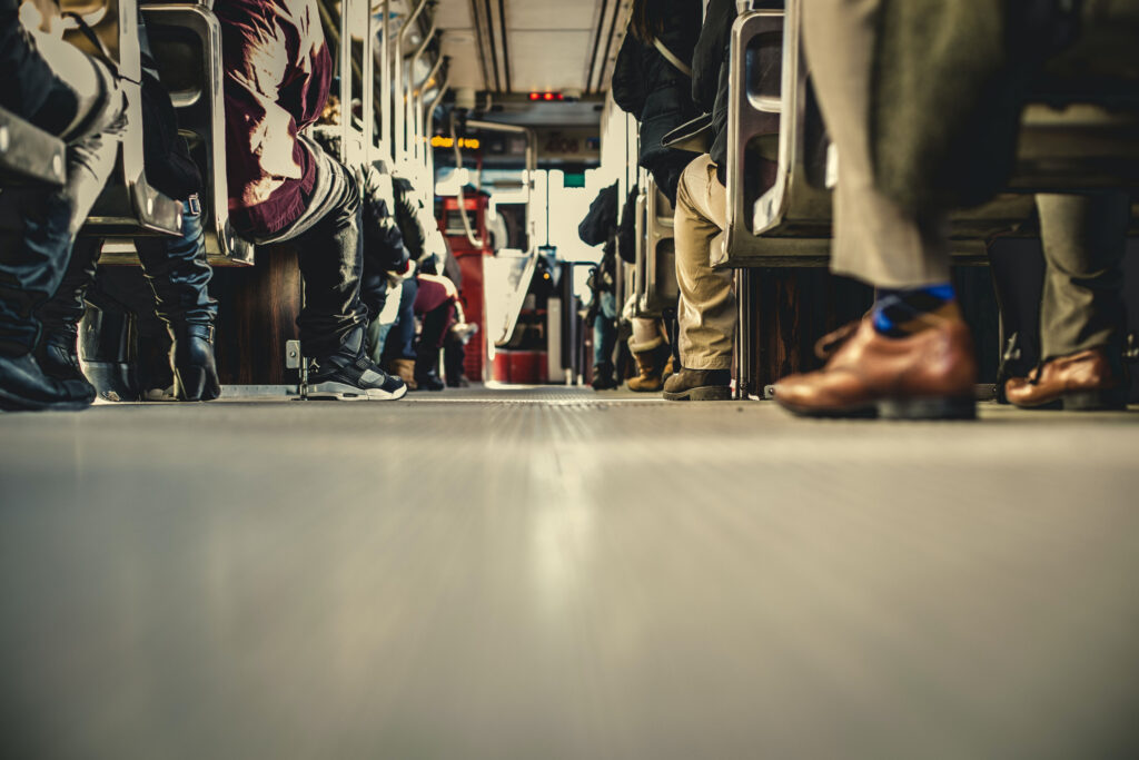 Voyageurs assis dans un train, pieds reposant sur le plancher.