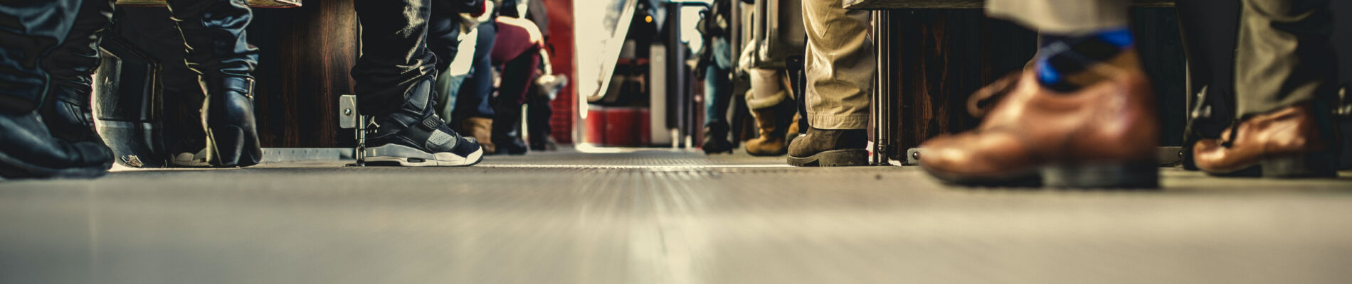Voyageurs assis dans un train, pieds reposant sur le plancher.
