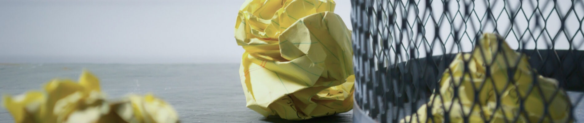 Poubelle avec des boules de papier jaune à l'intérieur et à l'extérieur.